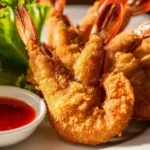 Oven-baked fantail shrimp with a light golden crust, served with a lemon wedge.